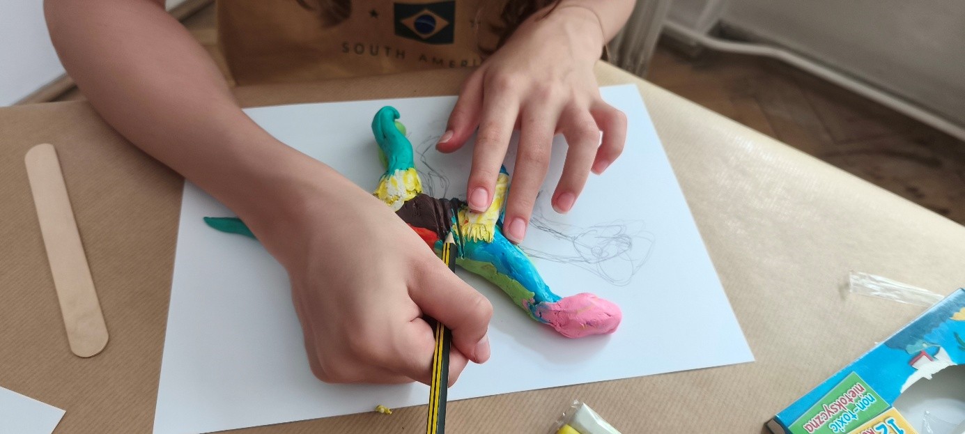 dziecko lepiące dinozaura z plasteliny