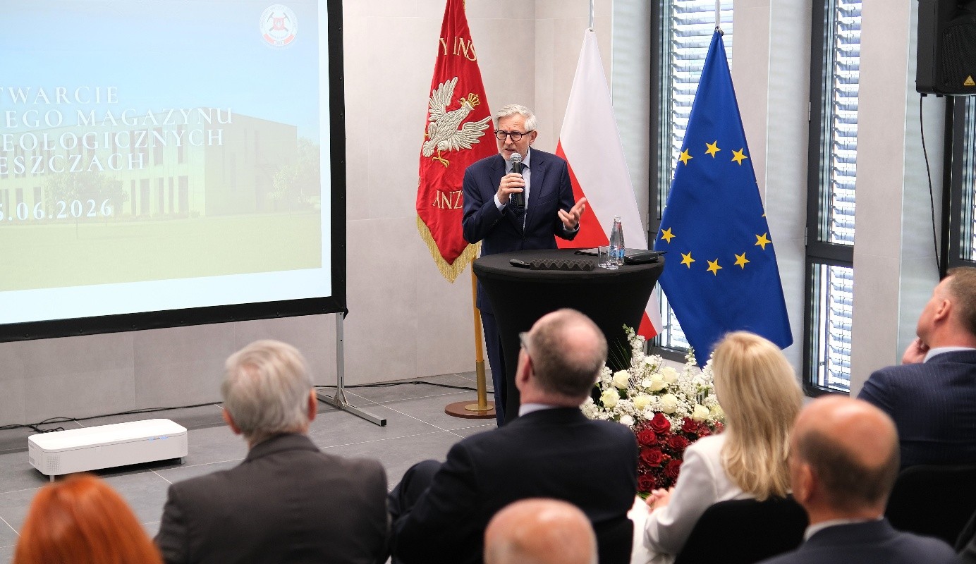 mężczyzna z mikrofonem w ręce podczas prelekcji, na tle ekranu