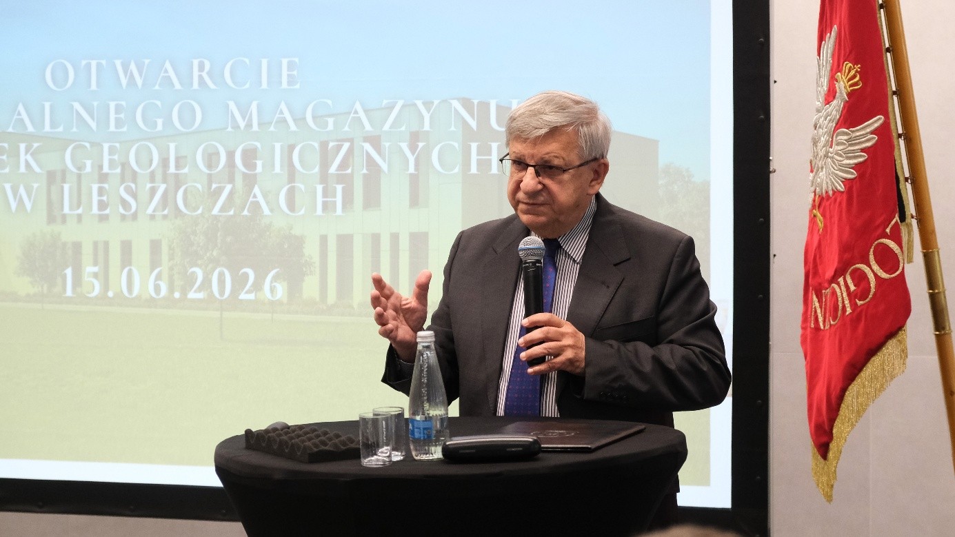 mężczyzna z mikrofonem w ręce podczas prelekcji, na tle ekranu
