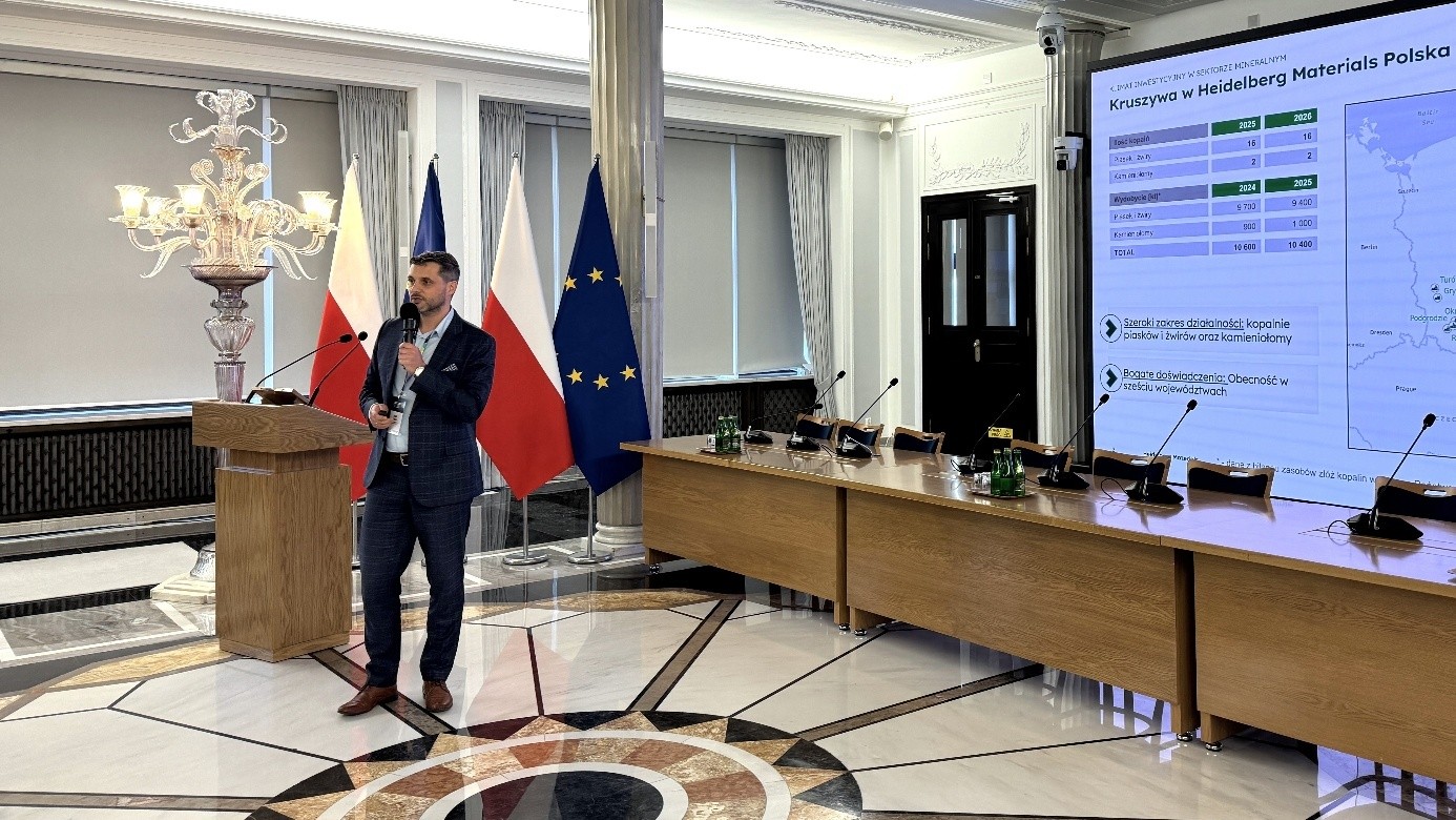 mężczyzna przemawia do siedzącej w pomieszczeniu publiczności