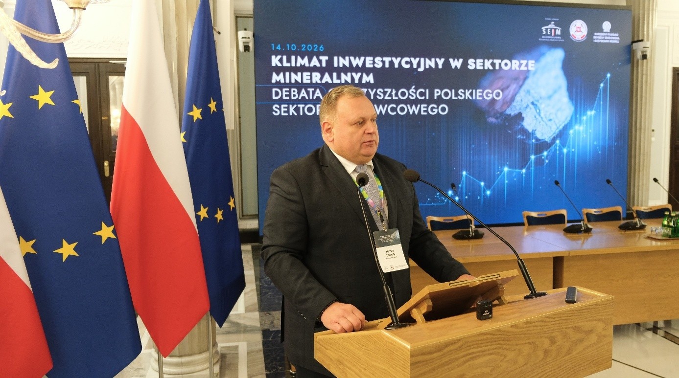 mężczyzna przemawia do siedzącej w pomieszczeniu publiczności