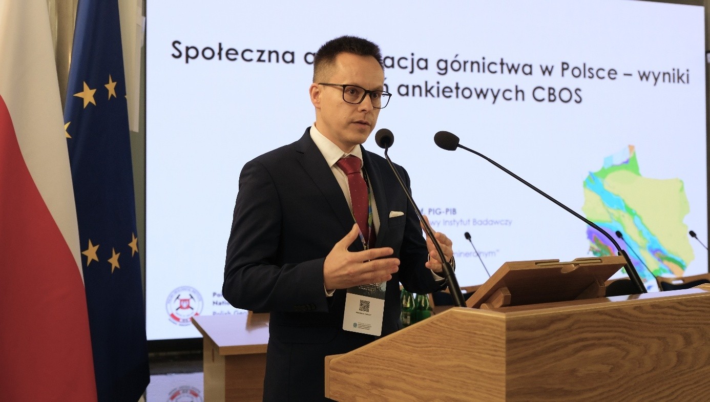 mężczyzna przemawia do siedzącej w pomieszczeniu publiczności