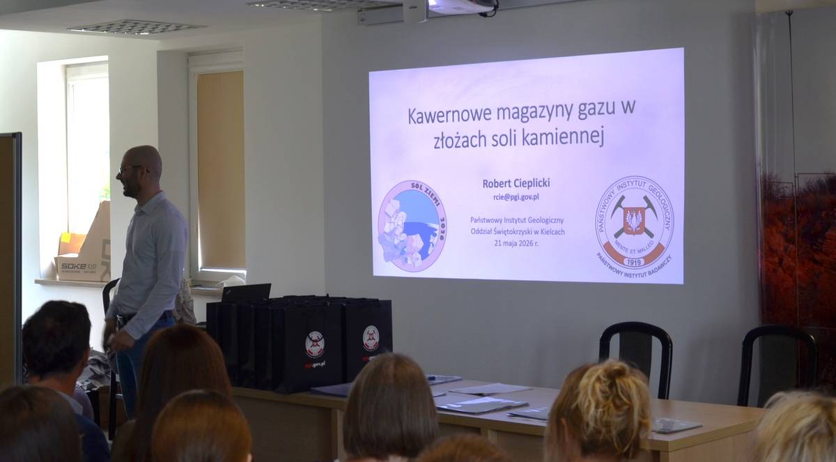 mężczyzna przemawia do siedzącej w pomieszczeniu publiczności